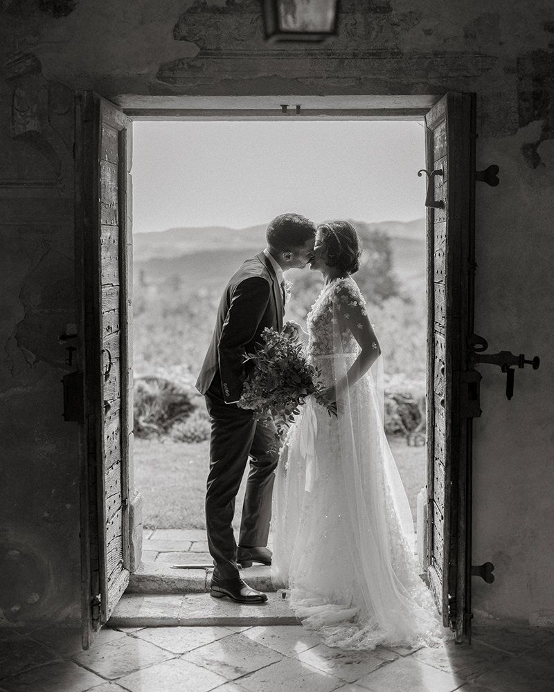 0036-chateau-de-bagnols-wedding-france-bride-groom-doorway-kiss-black-white